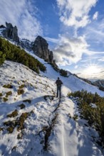 Hikers on a hiking trail with snow, sun star, ascent to Kramerspitz, in autumn, Ammergau Alps,