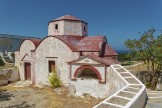 Traditional Mediterranean church on Platia Skopi with red roofs, surrounded by nature, under a