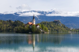 Church on an island in a lake, surrounded by mountains with snow, Bled Island with St Mary's