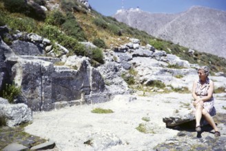 Woman female tourist sitting, archaeological site of Ancient Thera, Santorini, Cyclades islands,