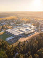 Large industrial plant in winter village, surrounded by forests at sunset, Neuweiler, Calw