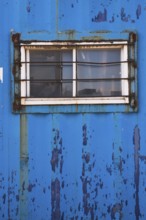 Blue painted metal building with window protected with steel bars, Quebec, Canada, North America