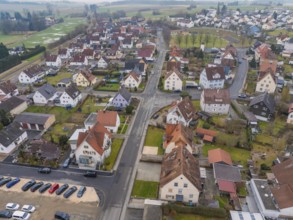 Cosy housing estate with red roofs and well-kept green spaces embedded in rural surroundings,