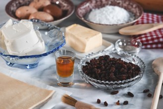 Baking ingredients such as sultanas, sugar, curd cheese and eggs on a kitchen table show a