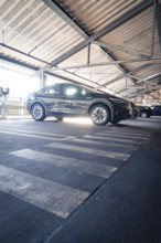 Black electric car parked under metal beams in a multi-storey car park in daylight, Kaufland Calw