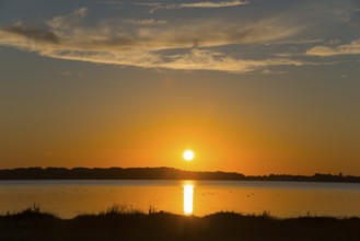 Sunset over a calm lake with silhouette on the horizon and bright sky in warm colours, Sunset,