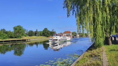 A peaceful river landscape with a boat and overhanging trees, Birkut ship, Elblag River, Elblag,