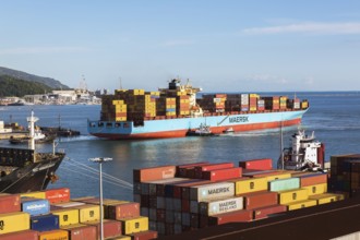 Maersk Serangoon cargo ship loaded with metal box shipping containers being guided by pilot boats