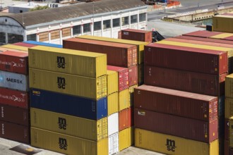 Stacked rectangular metal box shipping containers and warehouse building on dock in La Spezia cargo