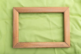 Wooden frame on smooth green linen tissue. Top view, flat lay, natural textile background and