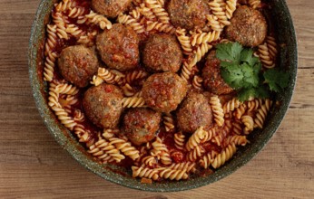 Minced meat meatballs, in tomato sauce, with fusilli pasta, in a cast-iron pan, homemade, no people