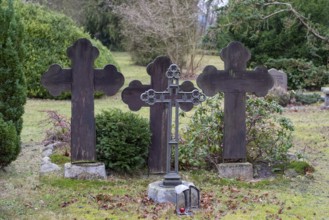 Three dark gravestones in a quiet cemetery, surrounded by bushes and bare trees, Seemannskirche