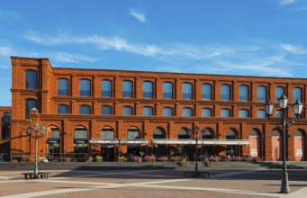 Red brick building with many windows under a clear blue sky, Manufaktura, Lódz, Lodz, Lodz, Poland,