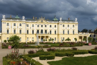 Yellow baroque castle with fountain in the decorated garden under a threatening sky, Branicki