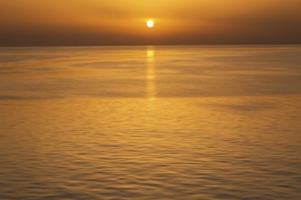 Setting golden sun over Adriatic sea taken from the top deck of a cruise ship in late summer, near