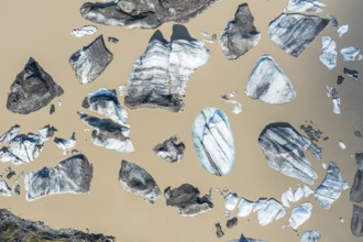 Glacier tongue of the Öræfajökull, small icebergs melting in the lagoon, muddy water, top down