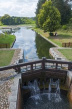 Lock and small waterfall in a picturesque river landscape with lush forest, Mikaszówka lock, Kanal