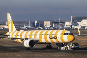 A Condor holiday airline aircraft is towed to the terminal by an aircraft tractor. Aircraft