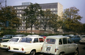 Cars in a car park next to a large modern office building, Great Britain 1966, location unknown