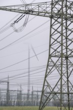 Wind farm in the fog, high-voltage pylons, dark doldrums, no wind no direct sunlight, in the