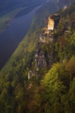 The bright lit Wartturm above the Elbe river seen from the Bastei rocks near the village of Rathen