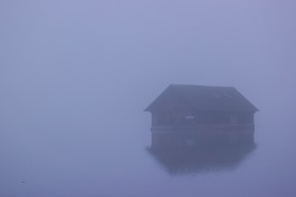 A Boatshelter at a lake in dense fog on an early fall morning