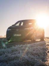 A car parked on a frosted meadow in the low sun, rays of light breaking through, car sharing,