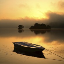 Sunrise on the Edersee with morning mist on the water, small islands in the Eder dam, fishing boat