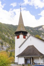 Small church with characteristic tower against an autumnal wooded mountain backdrop, Lauterbrunnen,