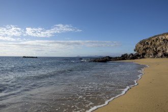 A quiet beach with gentle waves hitting the sand under a clear blue sky, Canary Islands, Lanzarote,