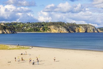 Young people playing volleyball on the sandy beach by the sea on a sunny summer day, Crozon