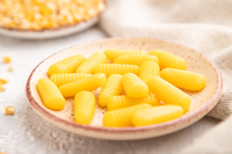 Jelly corn candies on gray concrete background and linen textile. side view, close up, selective