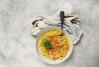 Risotto with shrimp, in a bowl, on a textured surface, with a side dish of fresh coriander,