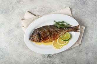 Baked dorado fish, in the oven, fried dorado, with spices and herbs, on a white plate, top view,