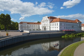 An impressive baroque castle on the riverbank with a canoeist in the water, Oranienburg Castle,