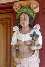 Atlant, figure of a woman with naked upper body, breasts, colourfully painted carving on the portal