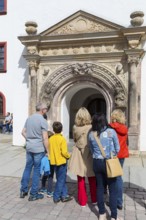 City guide with tourists in front of the Judith Lucretia portal with figurative carillon, Old Town