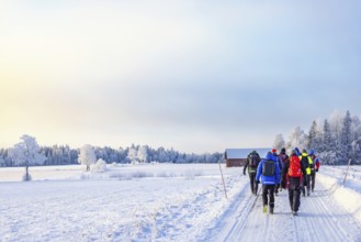 Group of people walking on a snowy road in a cold wintry rural landscape on a cold winter day,