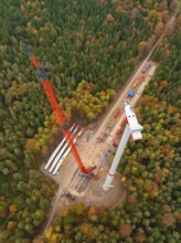 Construction work on a wind turbine above a forest in autumn, wind farm construction site,