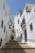 Steep narrow alleyway with white buildings and balconies under a blue sky, Old Town, Vejer de la