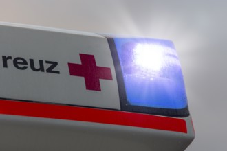 Close-up of an ambulance with flashing blue lights in the rain, Stuttgart, Baden-Württemberg