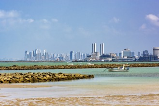 Boat on the beach in the city of Olinda with the skyscrapers of Recife in the background