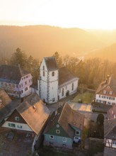 A church surrounded by half-timbered houses in the evening light creates a romantic atmosphere,