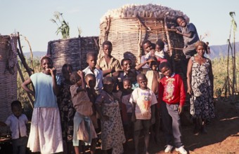 Villagers stand in front of a full maize store in a rural settlement, Malawi, southern Africa,