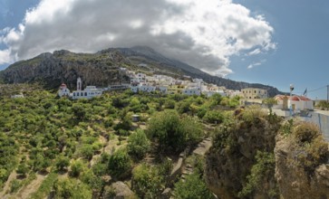 Picturesque mountain village of Mesochori under a white-blue sky and surrounded by a green valley,