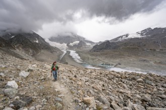 Mountaineer in bare stony mountain landscape, view of glacier Glacier de Cheilon and mountain peak