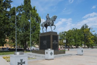 Monumental equestrian statue in a sunny park with surrounding vegetation, monument, equestrian