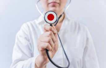 Female doctor holding stethoscope with Japan flag. National Health System of Japan