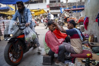 People gets a haircut at the street, on the day of the presentation of Union Budget, in Guwahati,