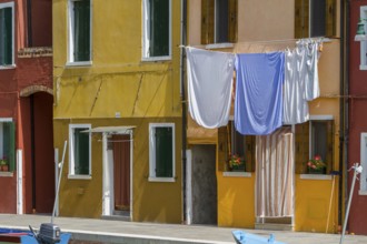 Laundry hangs on a yellow façade, the Mediterranean style creates a cosy atmosphere, Burano,